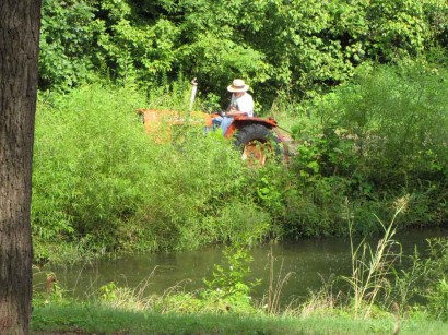 Driving Allis Chalmers tractor around pond mowing pond banks